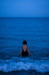 a woman sitting in the ocean at night